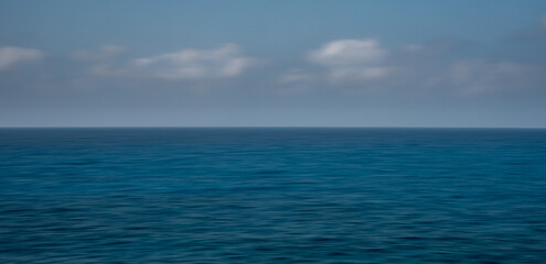 Fototapeta premium Panoramic seascape with clouds on the horizon. Blurry ocean seascape, serene and peaceful.