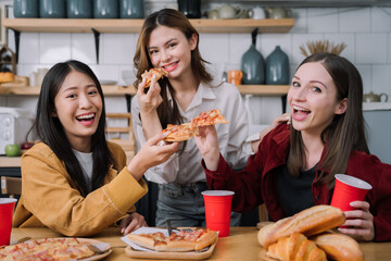 happy friends or teen girls eating pizza at home.
