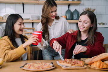 happy friends or teen girls eating pizza at home.