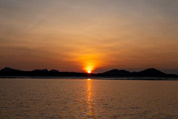 Sunrise view with colorful sky and the sea, with silhouette of the forest on the background