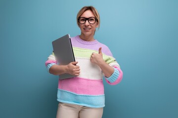 close-up photo of a european blond woman in a striped sweater using a laptop on a blue background...