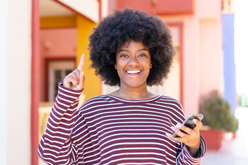 African American girl using mobile phone at outdoors pointing up a great idea