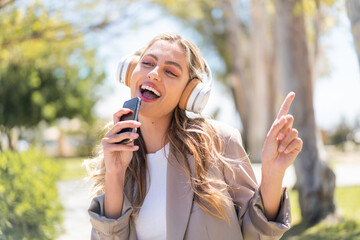 Pretty blonde Uruguayan woman listening music with a mobile and singing