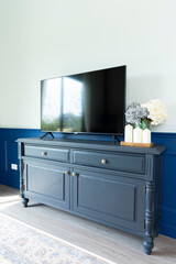 TV on a blue wood cabinet against a white wall in a home room.