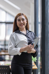 Portrait of Young business asian woman using tablet, standing in office.
