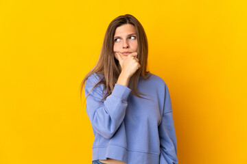Young Slovak woman isolated on yellow background having doubts and with confuse face expression