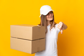 Young Slovak delivery woman isolated on yellow background showing thumb down with negative expression