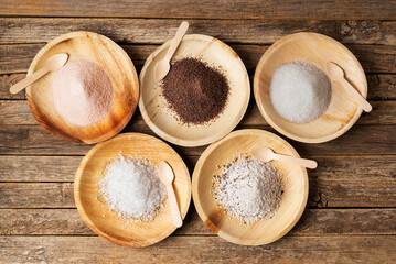 Wooden plates with different types of salt, pink, black, marine or normal, flakes and seasoned with truffle, on a rustic wooden table. Top view.