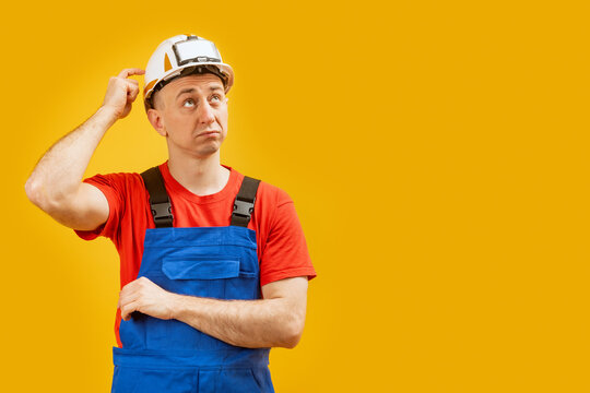 Portrait Of Disapointment Man Engineer Thinking And Looking Up. Builder Or Worker Wears Helmet And Uniform. Copy Space, Mockup