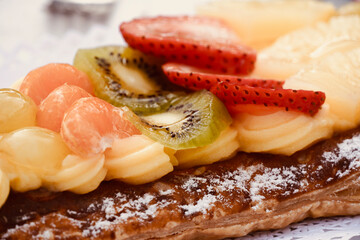 Fruit tart with cream puff pastry and white background. Sweet desserts with fruit and lights in the background. 