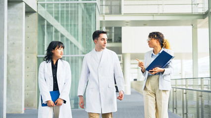 A multinational group having a conversation in the lobby.
People in white coats and sales staff.
