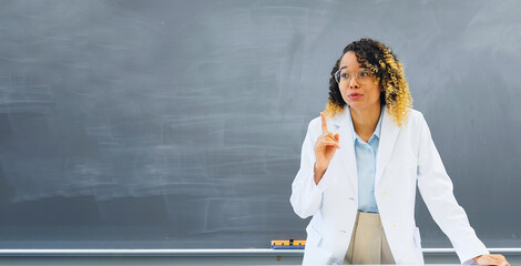 Female teacher teaching in front of the blackboard in the classroom.
