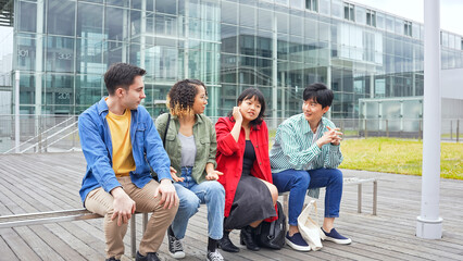 Fototapeta premium ベンチに座って話す多国籍学生グループ