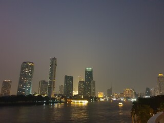 Photo of the view of the Chao Phraya River, Thailand, in the evening, seeing the hotel building by the river.