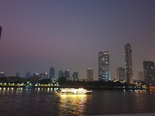 Photo of the view of the Chao Phraya River, Thailand, in the evening, seeing the hotel building by the river.