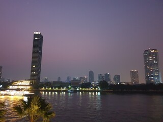 Photo of the view of the Chao Phraya River, Thailand, in the evening, seeing the hotel building by the river.