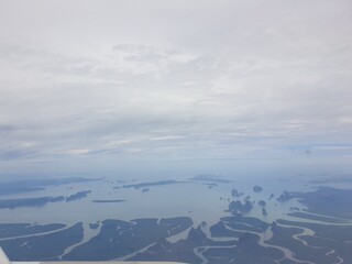 Top view from the plane, overlooking the sea, islands and wide blue sky.