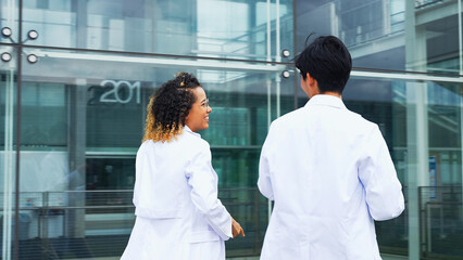 A multinational group wearing a white coat and walking through a facility.