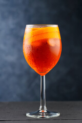 Aperol Spritz cocktail on dark wooden planks. Cocktail Aperol Spritz with oranges and ice cubes in glass. Traditional italian aperitif cocktail