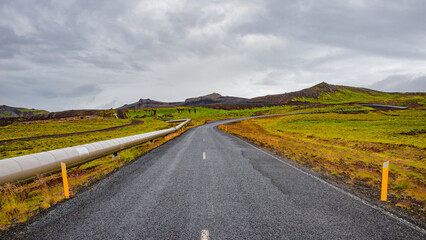 Panoramic over Icelandic colorful and wild landscape and geothermal pipeline going from a geothermal plant to Reykjavik city at summer time, Iceland