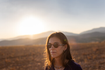 portrait of a beautiful young girl in glasses on a walk in the mountains. travel in the mountains at sunset.