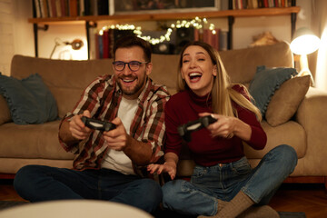 Obraz na płótnie Canvas Young couple having fun at home playing video games