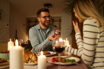 Fototapeta na wymiar Surprised woman getting a marriage proposal over romantic dinner at home