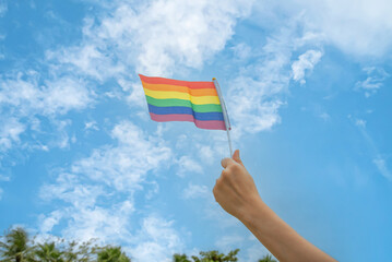 Diversity people hands raising colorful lgbtq rainbow flags together , a symbol for the LGBT community