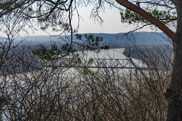 Landscape with a frozen river and trees in early spring in Russia.