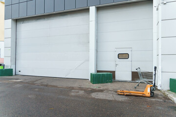Naklejka premium White roller shutters at the entrance to the store's warehouse. The place of unloading of goods and the entrance of trucks. Large high garage for trucks.