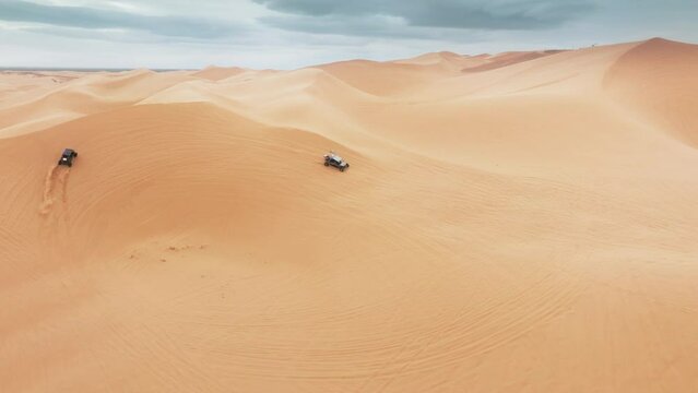 Aerial view of ATV buggy sport car riding fast by sand dunes. Group of four wheel drive vehicles competing on dunes. Extreme sport outdoor hobby on weekend day. Sport recreation concept for men 4K