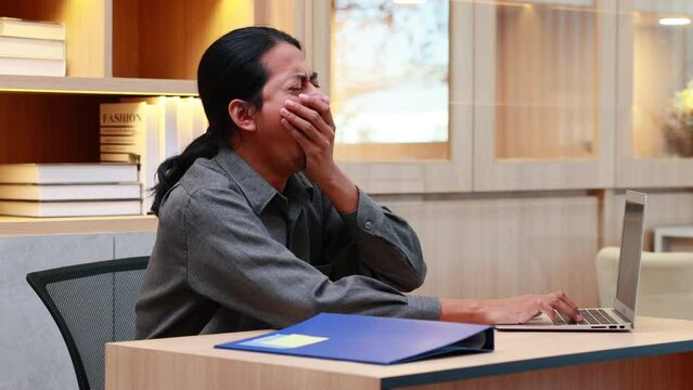 Exhausted tired Asian businessman slepping in home office work place.