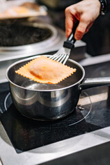 man chef hand cooking one big Ravioli on restaurant kitchen