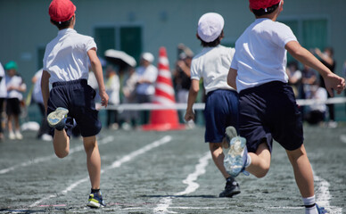 小学校の運動会で短距離走をしている学生達の後ろ姿