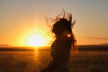 silhouette of a girl with her hair blowing in the wind at sunset