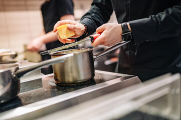 Chef hands cooking cheese sauce in the restaurant kitchen