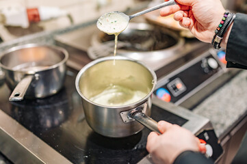 Chef hands cooking cheese sauce in the restaurant kitchen