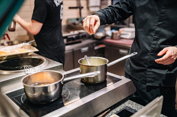 Chef hands cooking cheese sauce in the restaurant kitchen