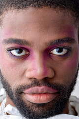 Obraz premium Male makeup look. close-up portrait of beautiful black young man with pink eyeshadow make-up. black american feminine womanlike guy confidently looking at camera. models, beauty, fashion concept