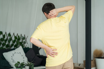 Back pain, man with backache at home on pink background
