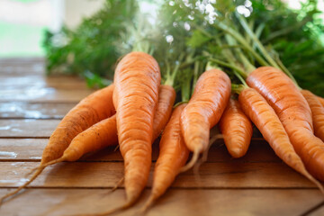 Bunch of fresh young carrots with haulm on a wooden table with copy space