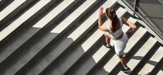Athletic woman runner in sportswear is training running up the stairs in the city Healthy lifestyle