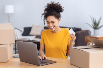 Smiling African American woman with credit card shopping online. Happy smiling female looking at...