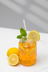 Fototapeta premium A glass of cold tea, ice cubes, lemon slices and a sprig of mint. Cooling summer drinks.