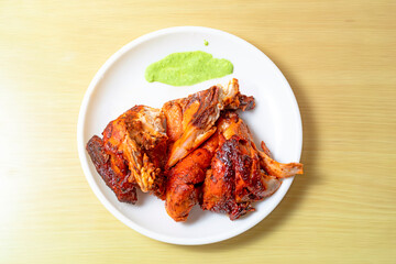 Grilled chicken wings on white plate with green sauce on wooden table