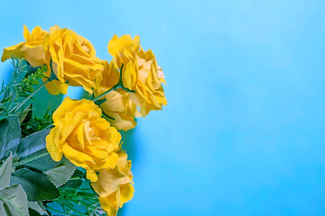 Bouquet of yellow roses on a blue background. Place for text.