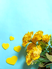 Bouquet of yellow roses and hearts on a blue background. Flat lay.