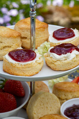 scones with jam, clotted cream and strawberries on an etagere in garden