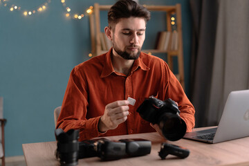 Male photographer ready to insert memory card to his professional DSLR camera while working in home...