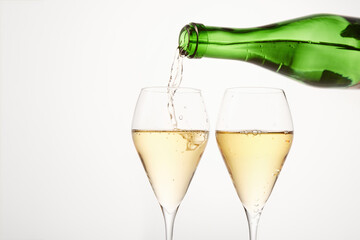 Sparkling wine pours from green bottleneck, creates bubbles.